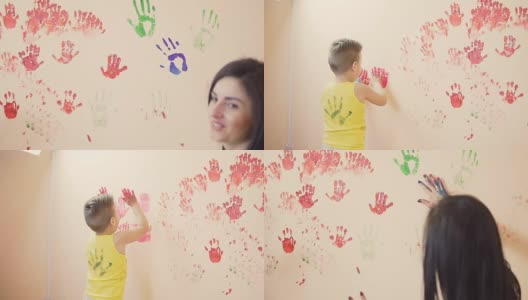 快乐可爱的小男孩和他年轻的妈妈在墙上留下五颜六色的手印玩得很开心。年轻的幸福的家庭。母亲和孩子的概念。Slowmotion高清在线视频素材下载
