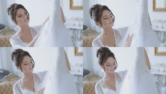 美丽的新娘穿着长袍看着婚纱高清在线视频素材下载