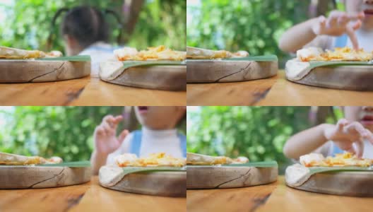 可爱饥饿的小女孩喜欢在后院吃自制的披萨。小女孩和家人在户外吃午饭。有选择性的重点。高清在线视频素材下载