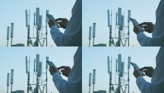 男子手持手机使用5G通信基站塔为背景高清在线视频素材下载
