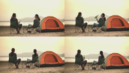 两个露营的女人喝着啤酒享受日落，看着美丽的山高清在线视频素材下载