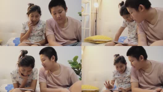 亚洲儿童晚上在家里一起在沙发上用智能手机看电影或视频，生活理念。高清在线视频素材下载