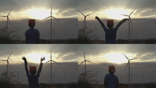 一个以风力涡轮机为背景的男孩剪影。高清在线视频素材下载