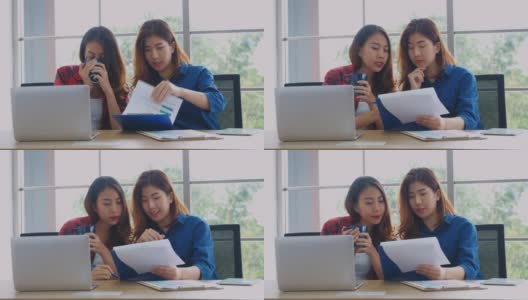 两个年轻的亚洲女性工作文书工作和喝咖啡在家办公室与幸福，办公室休闲的生活方式高清在线视频素材下载