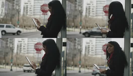 一名年轻女子一边玩着平板电脑，一边等公交车高清在线视频素材下载