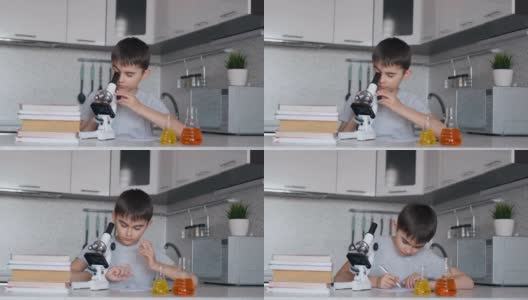 一个男孩用显微镜学习生物，并在笔记本上做笔记。家庭作业高清在线视频素材下载