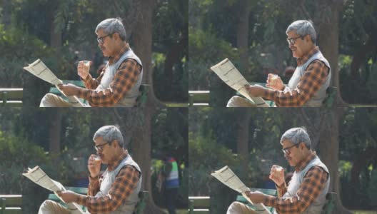 老人在公园长椅上喝茶看报纸高清在线视频素材下载