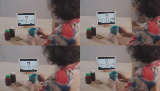 远程医疗的亚洲老年患者女性使用笔记本电脑视频通话的女医生，护士在家里的客厅高清在线视频素材下载