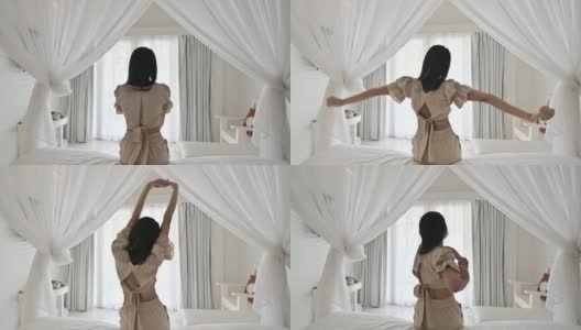 一个年轻的亚洲女人在度假的早上在床上伸展手臂高清在线视频素材下载