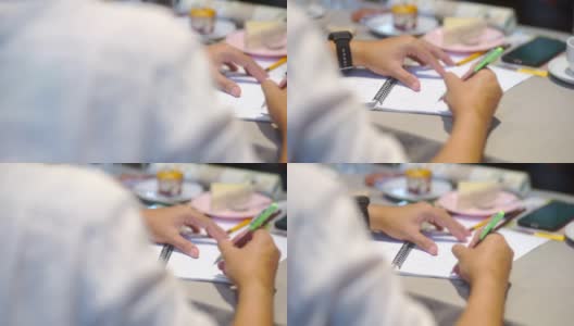 一个亚洲人在办公室会议桌上的书上写字高清在线视频素材下载