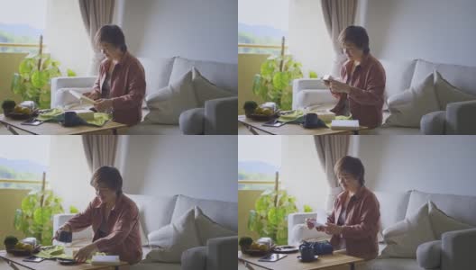亚洲华人中年妇女在客厅打开月饼礼盒读贺卡高清在线视频素材下载