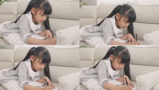 女孩在家里的客厅里做作业和画画高清在线视频素材下载