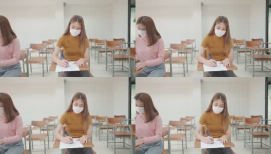 一群女学生戴着面具坐在大学教室里学习和考试，这是新常态。高清在线视频素材下载