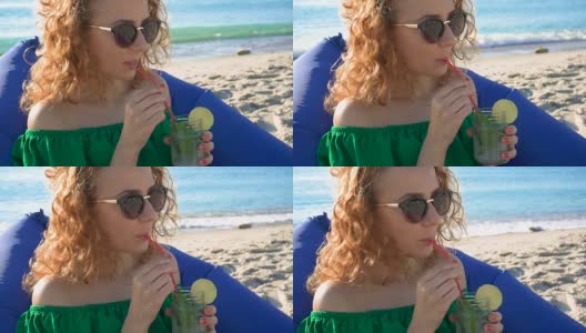 年轻女子在海边享用热带莫吉托鸡尾酒和新鲜的酸橙高清在线视频素材下载