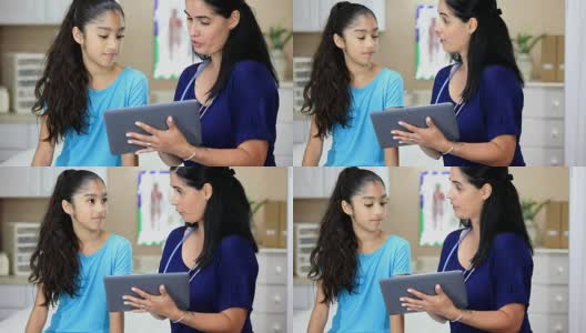 拉丁女医生拿着数字平板电脑。她正在给年轻的拉丁女病人做体育检查。高清在线视频素材下载
