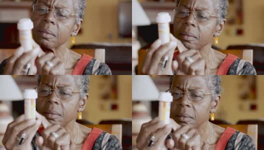 非裔美国老年妇女试图阅读她手中的药瓶标签高清在线视频素材下载