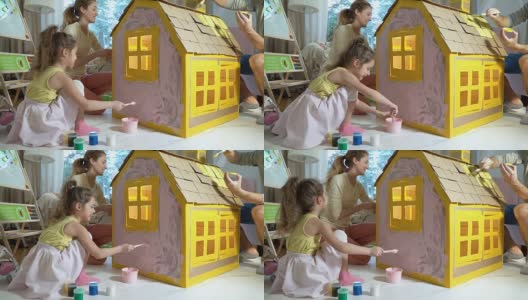 年轻的家庭和孩子一起建造和油漆玩具纸板房子高清在线视频素材下载