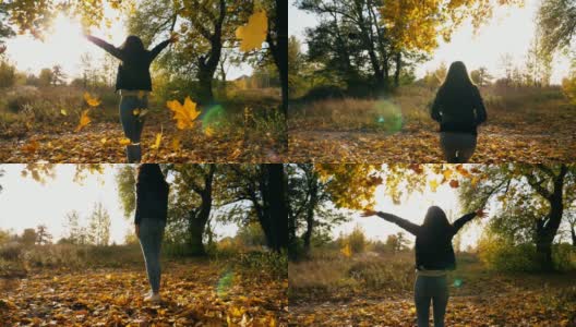 一个陌生的年轻女子在秋天的公园里跳着，扔着黄色的枫叶。彩叶飘落。女孩举起手，享受这一刻。美丽的自然景观。慢动作高清在线视频素材下载