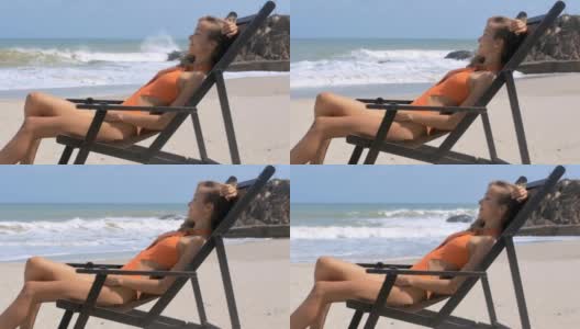 快乐的女人在沙滩上的木椅上放松高清在线视频素材下载
