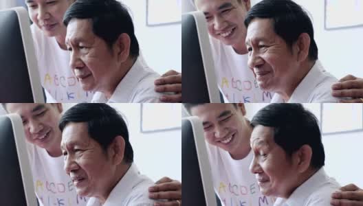 Senior man learn to use computer. Asian senior man with young man in his home. Happy smile.高清在线视频素材下载