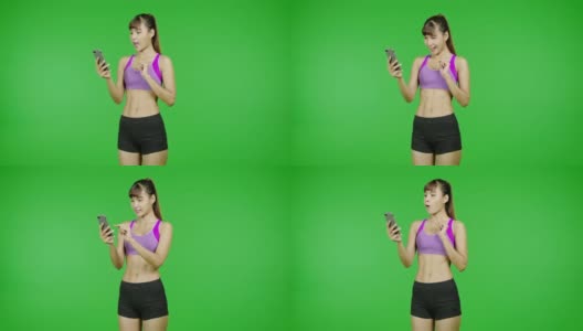 Fit woman浏览手机，惊喜，销售，绿屏背景，Fit body, social media communication。亚洲女运动员穿着紫色的衣服站在镜头前。高清在线视频素材下载