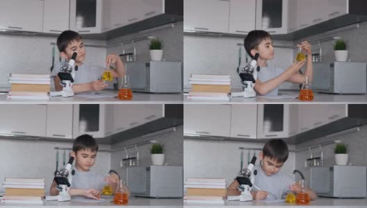 这个男孩用显微镜和装有液体的瓶子学习生物，并在笔记本上做笔记。家庭作业高清在线视频素材下载