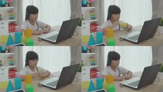 亚洲女学生视频会议e-learning几何形状与老师和同学在家里的客厅电脑上。在家教育和远程学习，在线，教育和互联网。高清在线视频素材下载