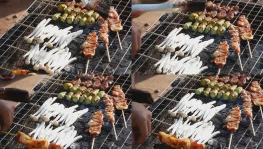 云南式烧烤:肉、鱿鱼、蘑菇和猪肉在木炭烤架上烧烤，配以海鲜酱或中国辣药草食用。当地市场上的泰国美味街头小吃。高清在线视频素材下载