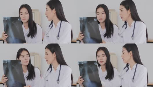 两名身穿实验室大褂的亚洲妇女在医院工作，其中一名妇女拿着一张x光片，正在和另一名妇女交谈。高清在线视频素材下载