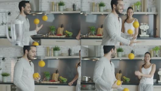 一个活泼的年轻人用厨房里的橙子杂耍来打动他的女朋友。高清在线视频素材下载