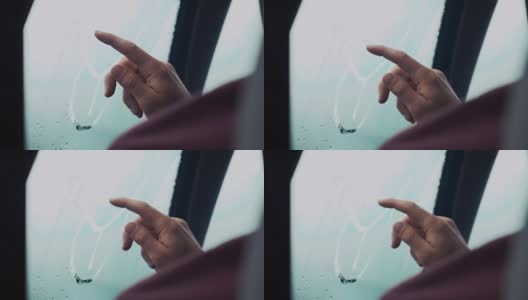 一名男子用一根手指在车窗上画画。外面下雨的天气。滴高清在线视频素材下载