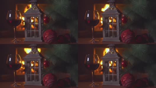 桌上放着一杯红酒，一盏圣诞灯和一棵圣诞树。背景-壁炉与火焰。新年假期酗酒。酒精饮料。火的背景。独自喝。餐厅的饮料高清在线视频素材下载