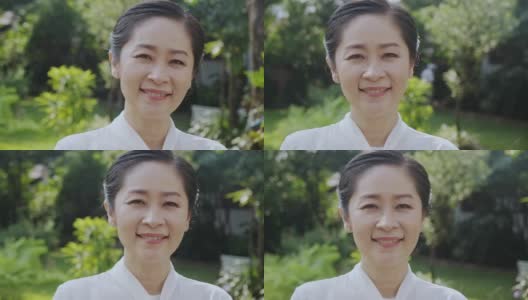 漂亮的亚洲中年妇女肖像与美丽的家花园的背景。高清在线视频素材下载