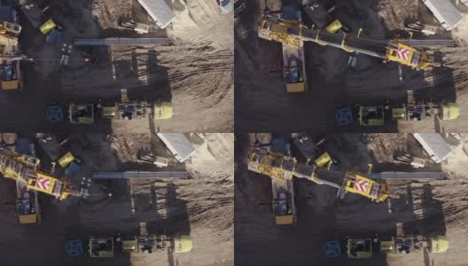 在一个阳光明媚的日子里，一架无人机在山谷里的一个石油和天然气钻井平台上直接拍摄了起重机拆卸钻机的画面高清在线视频素材下载
