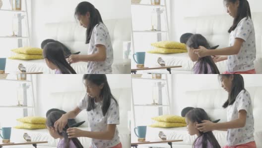 手亚洲女孩在家里编她的姐姐的头发，孩子一起玩，生活理念。高清在线视频素材下载