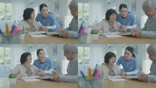 迷人的年轻老年亚洲公民夫妇坐在家里水彩画艺术品桌上与护士在心理健康治疗或亚洲老年人隔离活动生活方式感到快乐。高清在线视频素材下载