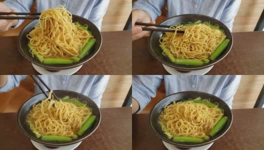 用筷子将一碗新鲜的中国鸡蛋面与清淡的汤轻轻混合高清在线视频素材下载