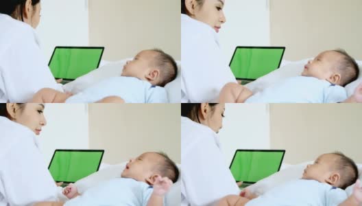 妈妈和宝宝在笔记本电脑上工作，绿色的屏幕背景。高清在线视频素材下载