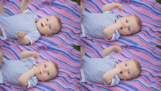 一个漂亮的蓝眼睛的小孩躺在彩色的毯子上。高清在线视频素材下载