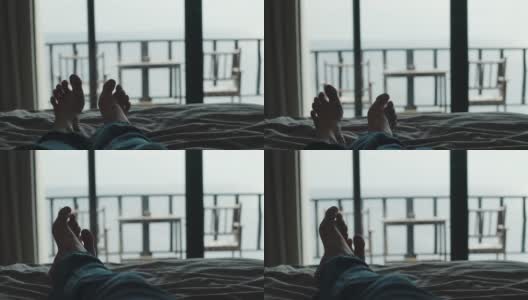 放松的人们躺在床上，交叉腿在毯子上，在酒店度假胜地看风景高清在线视频素材下载