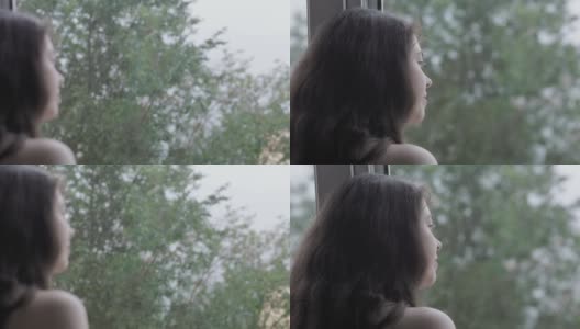 秋天的天气。一个微笑着做梦的女人的肖像扔在窗户上看着雨。后视图。关闭了。心理学的概念高清在线视频素材下载