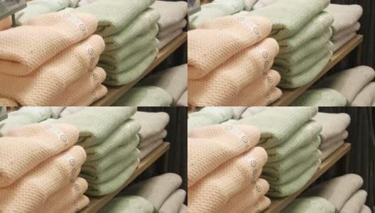 漂亮暖和的浅色女式针织衫在服装店的货架上折叠成一排高清在线视频素材下载