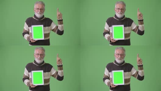Handsome senior bearded man wearing warm clothing against green background高清在线视频素材下载