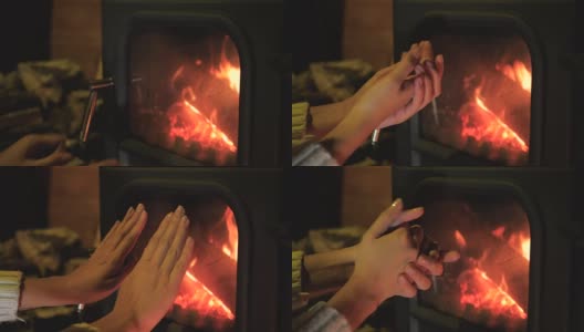 女人把冻僵的手拿到壁炉前取暖高清在线视频素材下载