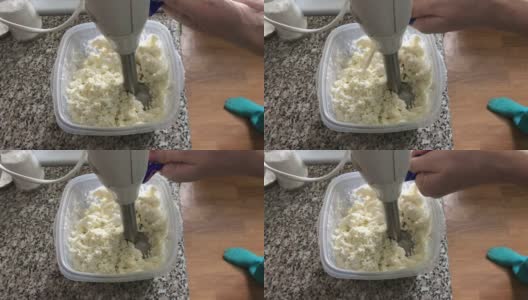 一位女士在容器中加入酸奶油和白软干酪。用于制作软干酪甜点。高清在线视频素材下载