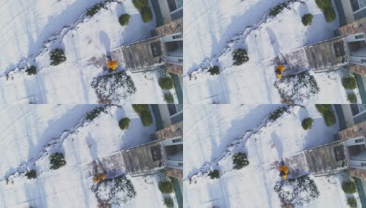 一场冬季降雪后，一名50岁的长头发、身穿黄色夹克的男子用铁铲在乡村房屋前院的小路上清理积雪。高清在线视频素材下载
