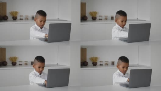 在线教育可爱的小黑人男孩在家里用笔记本电脑打字高清在线视频素材下载