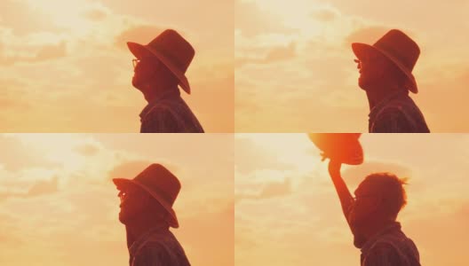夕阳下，老农民站在稻田里的剪影。一位戴着帽子的老人在金色的天空背景上望着远方。高清在线视频素材下载