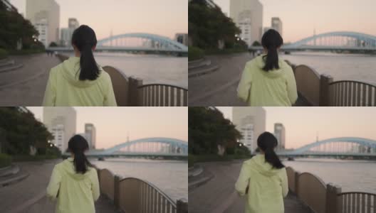 落日时分，东京，一名女子在河边奔跑的背影高清在线视频素材下载