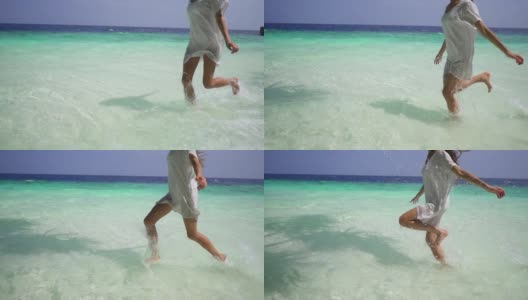 马尔代夫，一名身穿白色连衣裙的美丽年轻女子在碧绿的海水中奔跑。奇异的热带植物。缓慢的运动。高清在线视频素材下载